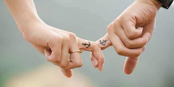 Paar mit Ankertattoo hält Händchen
